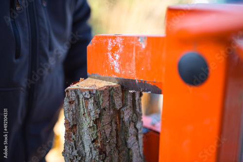 Close-up shot of a hydraulic wood splitter cutting fire wood on a sunny day photo