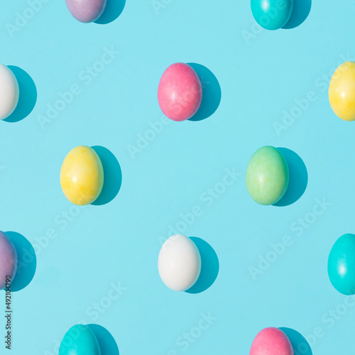 Trendy pattern made of colorful Easter eggs on bright blue background. Minimal Easter concept. Creative food layout.
