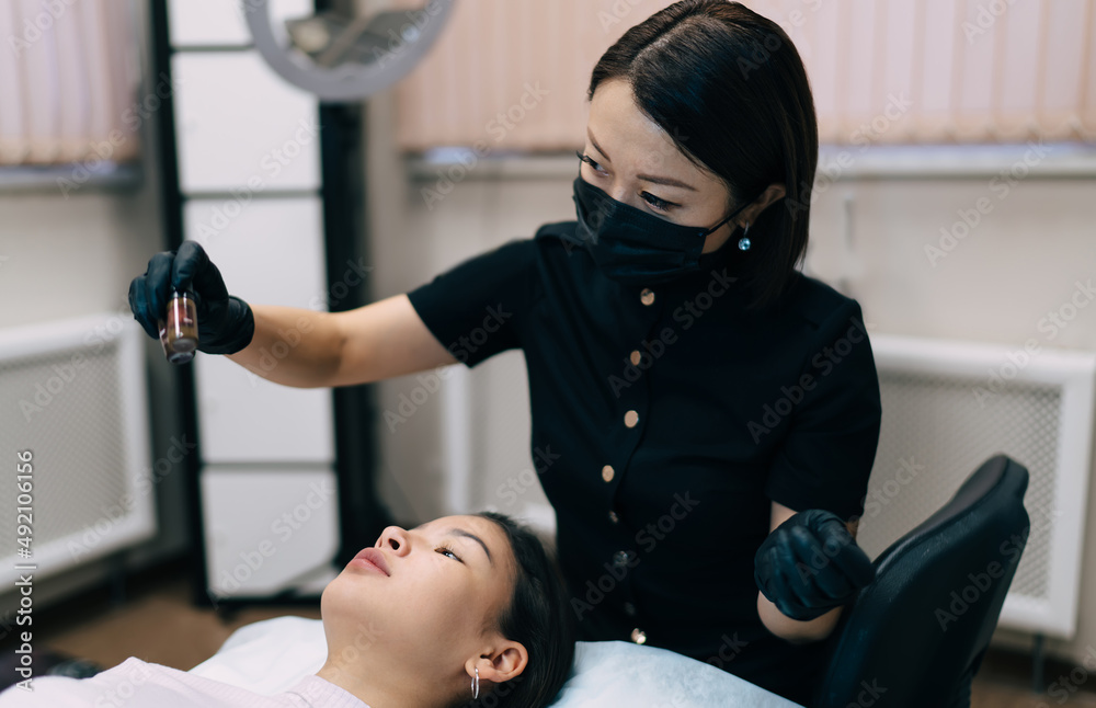 Fototapeta premium Beautician do eyebrow microblading of asian girl