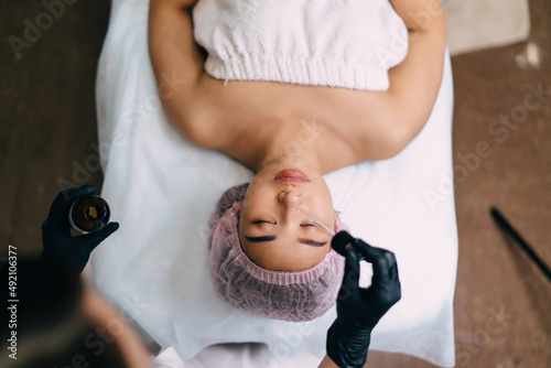 Beautician dripping oil with dropper on girl face