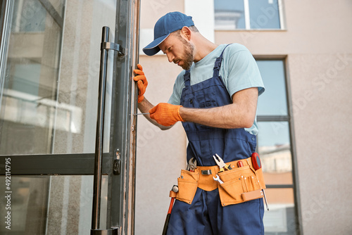 Bearded young man repairing door in building