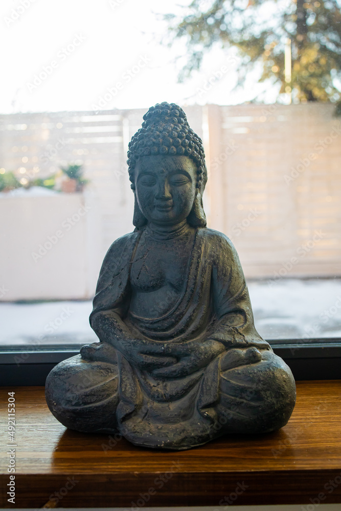 Meditating Buddha Statue stone sculpture of asian buddha in room.