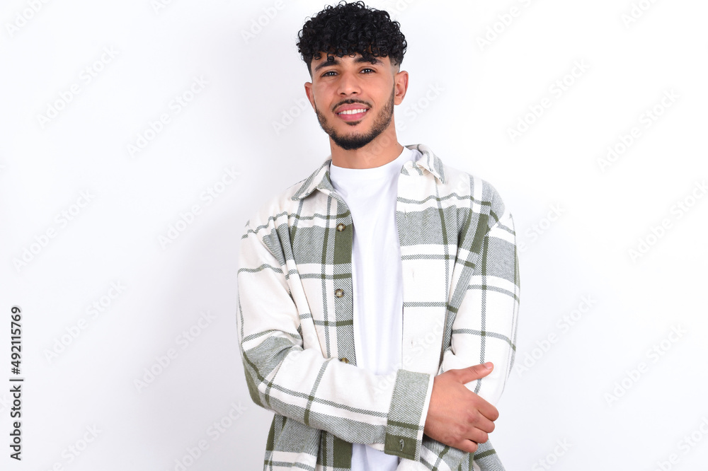 young arab man with curly hair wearing overshirt over white background laughing. young arab man with curly hair wearing overshirt over white background laughing.
