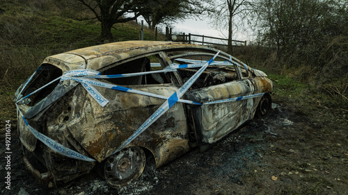Burnt out car wrapped in police tape