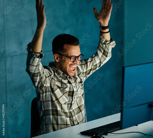 businessman working late night business computer man office technology light dark happ success celebrate victory deadline work photo