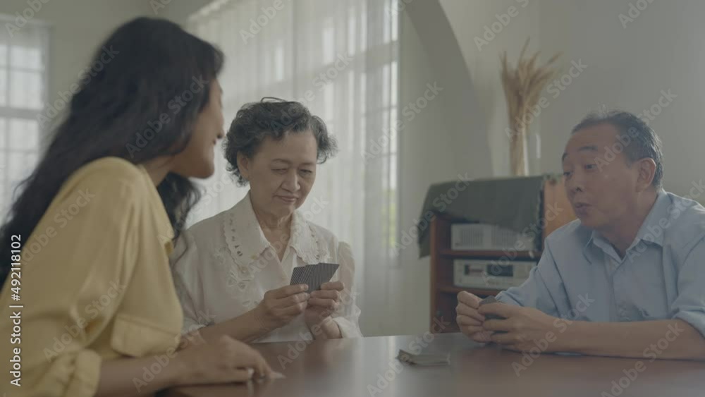Holiday concept of 4k Resolution. Asian families take turns discarding cards on the table while playing games at home. Family gambling games. Holiday concept of 4k Resolution. Asian families take turns discarding cards on the table while playing games at home. Family gambling games.