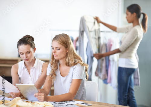 Designing the new range. Three young multi-ethnic fashion designers working in their studio.