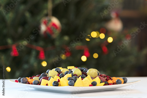 Mixed fruit salad on a white table with Christmas tree background