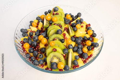 Mixed fruit salad in a glass bowl on white background