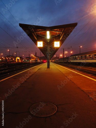 Railway platform with clock and a manhole in night city lights background