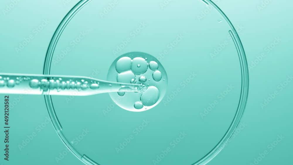 Close up view macro shot of gel with different sized bubbles comes out from lab dropper into petri dish on cyan background | Abstract face care gel with hyaluronic acid mixing concept