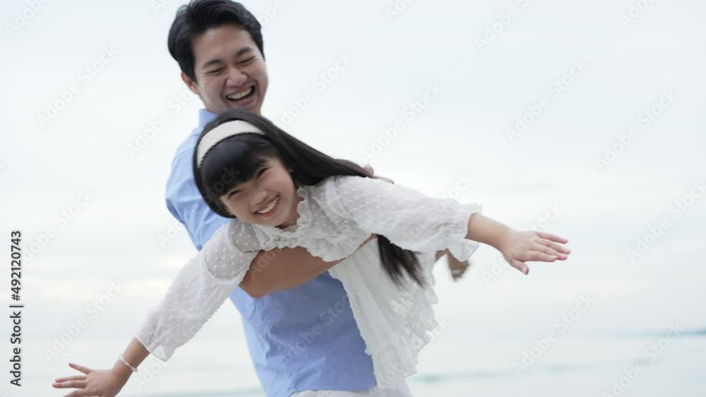 Holiday concept of 4k Resolution. father playing with daughter on the beach. Asian girl moving her hand to fly. Holiday concept of 4k Resolution. father playing with daughter on the beach. Asian girl moving her hand to fly.