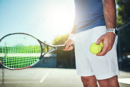 Meet me on the court. Cropped shot of an unrecognizable male tennis player holding a tennis ball and racket on a tennis court outdoors. © Allistair F/peopleimages.com