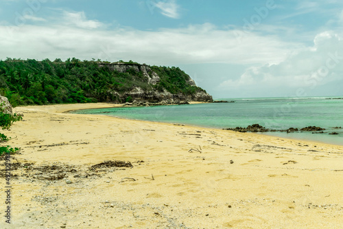Fototapeta Naklejka Na Ścianę i Meble -  Linda praia com algumas pedras, pessoas tomando banho, montanhas com mata verde ao redor e paisagem marítima ao fundo com ondas e nuvens, localizada na Praia dos Espelhos, Bahia.