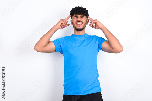 Photo of crazy young arab man with curly hair wearing blue t-shirt over white background screaming and pointing with fingers at hair closed eyes