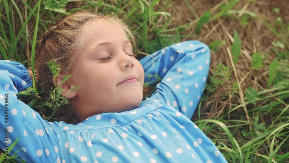 little girl child lies on the grass in the park. happy family kid dream concept. baby girl in the park lies on fun her back looks at the sky portrait close-up. girl in nature smiling portrait little girl child lies on the grass in the park. happy family kid dream concept. baby girl in the park lies on fun her back looks at the sky portrait close-up. girl in nature smiling portrait
