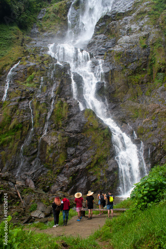 group of young people in hats admiring a large waterfall with falling water. 