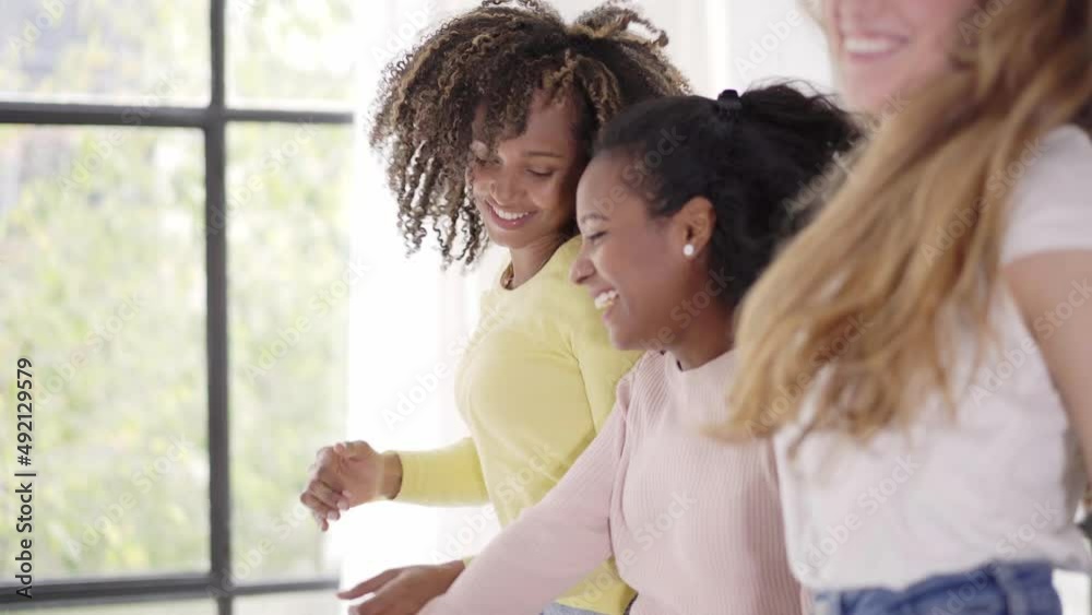 Three rebellious women friends dancing and singing on the sofa. Cheerful girls enjoy together at home having fun. Three rebellious women friends dancing and singing on the sofa. Cheerful girls enjoy together at home having fun.
