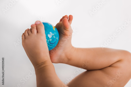 close up earth globe map holding by baby legs on white background