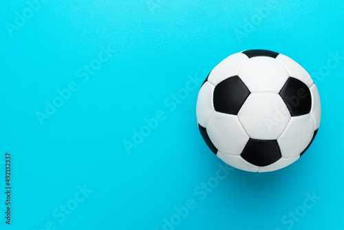 Top view photo of white and black soccer ball as football concept . Minimalist flat lay image of leather football ball over blue turquoise background with copy space and right side composition.