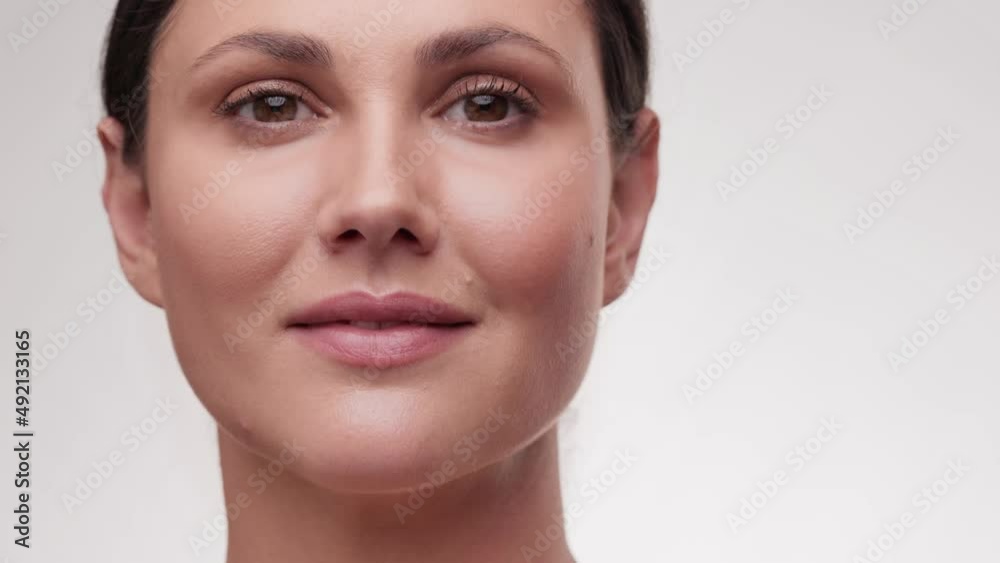 Beauty face. Smiling brunette woman look at the camera. Healthy skin portrait. Beautiful happy female model with fresh glowing hydrated facial skin and natural makeup on light background at studio. Beauty face. Smiling brunette woman look at the camera. Healthy skin portrait. Beautiful happy female model with fresh glowing hydrated facial skin and natural makeup on light background at studio.
