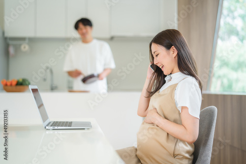 テレワークする妊婦と家事をする男性（電話）
