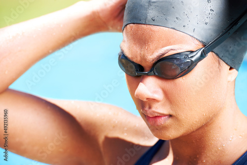 Finding her focus and feeling determined. Determined young female swimmer looking away - closeup.