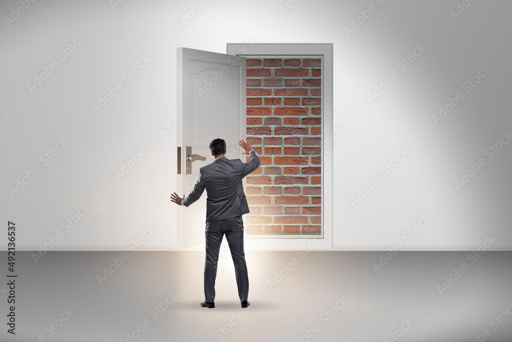 Businessman facing no exit with brick door Businessman facing no exit with brick door