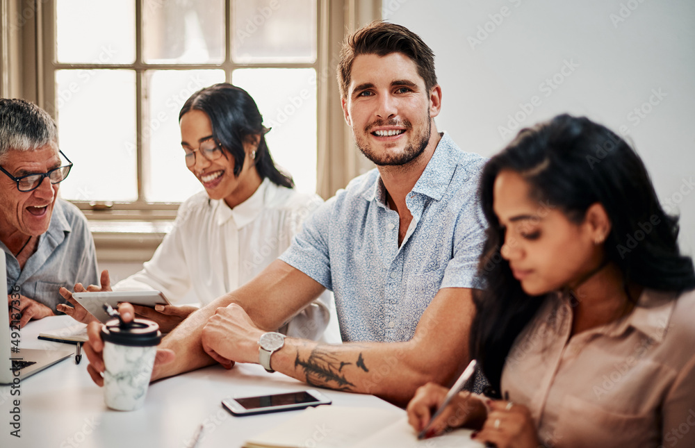 The best team ever is sitting right behind me. Portrait of a young businessman having a meeting with colleagues in a modern office. The best team ever is sitting right behind me. Portrait of a young businessman having a meeting with colleagues in a modern office.
