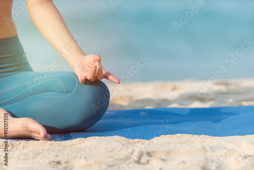 yoga on the beach. yoga woman doing flexibility yoga exercise on mat. Peaceful girl sitting in forward bend exercise, head to knees Uttanasana pose, outdoor woman doing gymnastic physical training exe