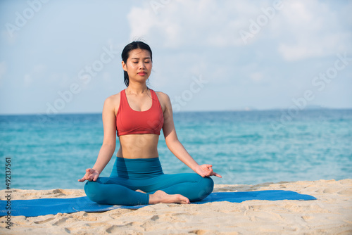 woman doing yoga. Asian yoga girl doing flexibility yoga exercise on mat. Peaceful girl sitting in forward bend exercise, head to knees Uttanasana pose, outdoor woman doing gymnastic physical training