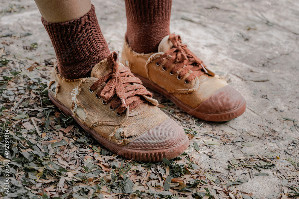 Foto Stock Torn student shoes, Poverty of rural schoolchildren often cannot  afford new shoes, high school student legs wearing torn shoes, poor shortage  of educational equipment, worn-out brown old sneakers | Adobe