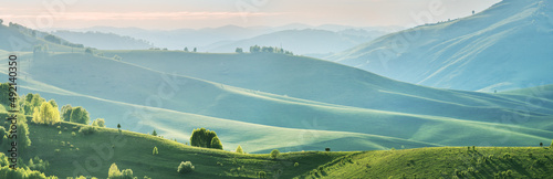 Evening light and spring greenery of hills and mountain slopes, panoramic view
