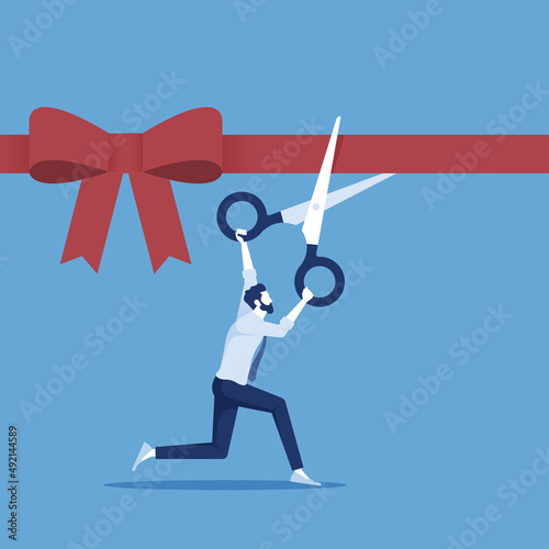 Grand opening concept, businessman holding pair of scissors in hand cuts red tape with bow