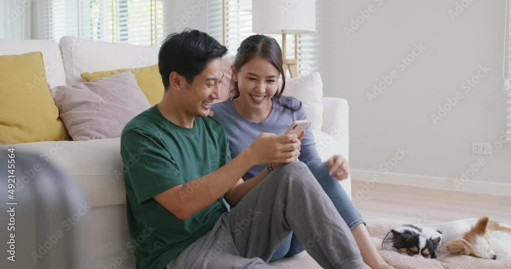 Asia people young family man woman smile happy fun laugh look at phone sit at home pay for hotel booking, search choose, buy ticket on social media app for budget travel abroad trip getaway plan tour.