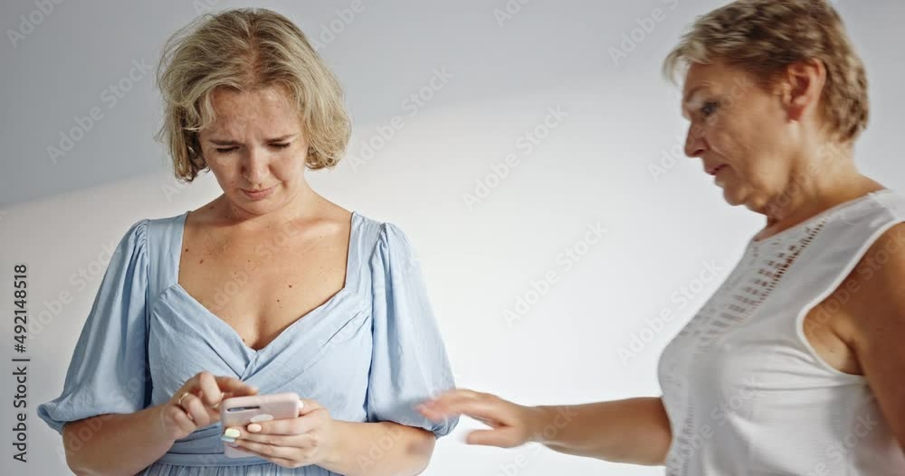 Angry and nervous mother with index finger up scolding her scared daughter with smartphone. Family and modern technology addiction concept. Angry and nervous mother with index finger up scolding her scared daughter with smartphone. Family and modern technology addiction concept.