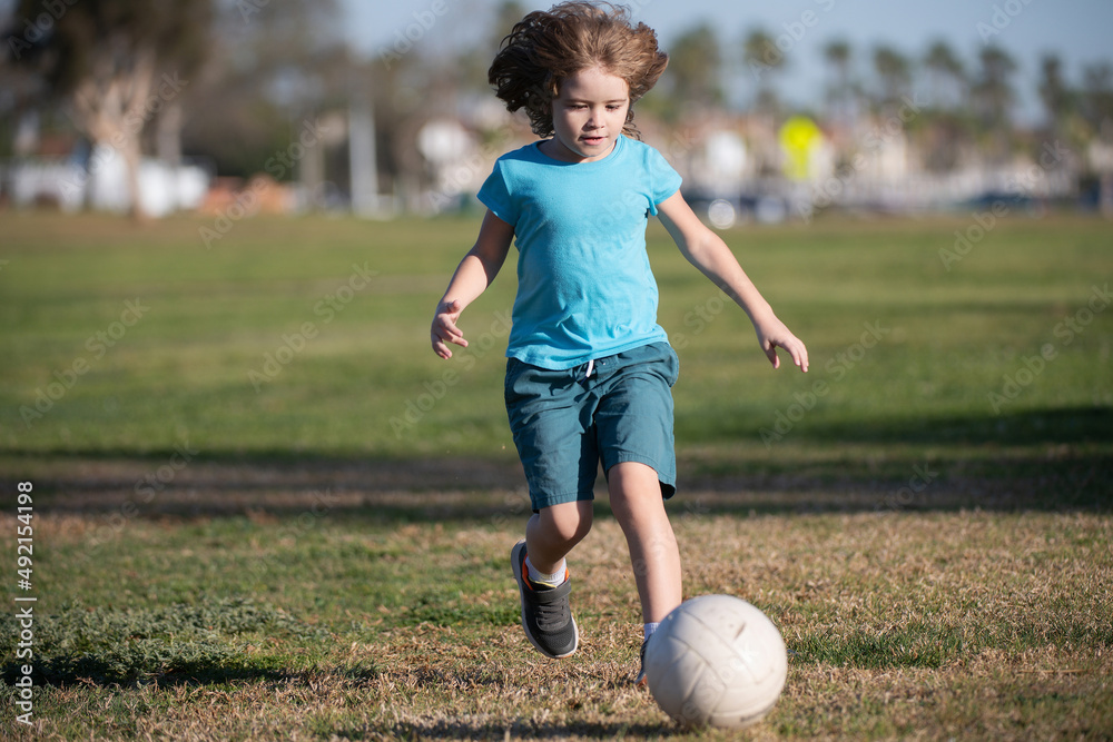 Boy football player kicking football on the sports field. Active kids. Child soccer. Child soccer play football in park. Boy football player kicking football on the sports field. Active kids. Child soccer. Child soccer play football in park.