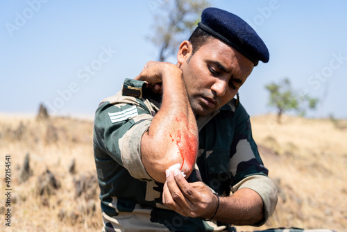 Fototapeta suffering injured or wounded soldier treating himself during training or warfare