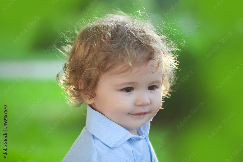 Baby playing in green grass. Baby face closeup. Funny little child close up portrait. Blonde kid, emotion face. Baby playing in green grass. Baby face closeup. Funny little child close up portrait. Blonde kid, emotion face.