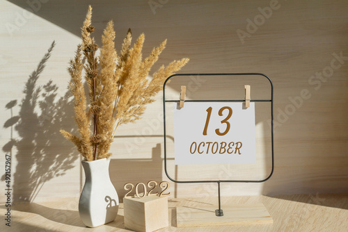 october 13. 13th day of month, calendar date. White vase with dead wood next to the numbers 2022 and stand with an empty sheet of paper on table. Concept of day of year, time planner, autumn month