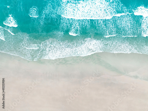 Top view of the Coast with waves as a background from aerial view. Blue water background from drone. Summer seascape from above Travel