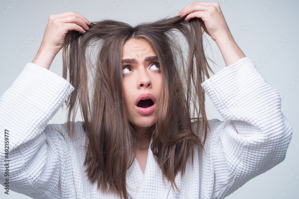 Fototapeta premium Sad woman looking at damaged hair, the hair loss problem. Studio isolated portrait, copy space.