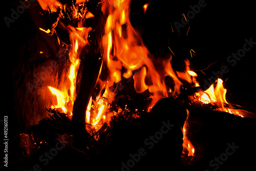 Camp fire during night. Heat heap closeup view with red and yellow flames. Burning and blazing fire.