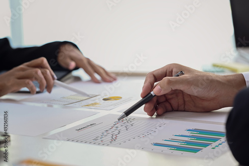 Close up view group of financial advisor analyzing graph together at office desk.