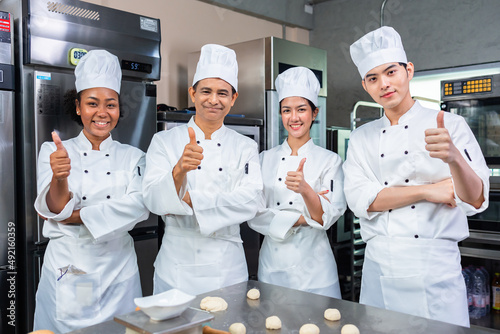 Asian Chefs baker in a chef dress and hat, cooking together in kitchen.Team of professional cooks in uniform preparing meals for a restaurant in the kitchen.