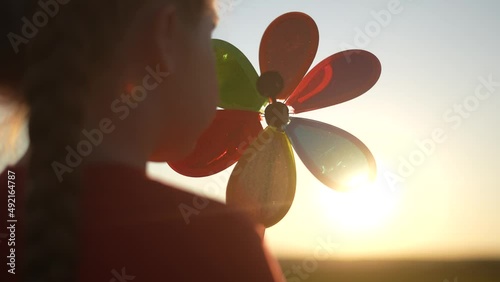 kid pinwheel. little baby girl silhouette play with windmill toy wind in the park. happy family kid dream concept. baby fun girl play toy pinwheel the glare sunset of the sun at in the park photo