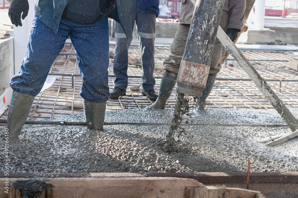 Foto de Builders workers pour concrete floor in industrial