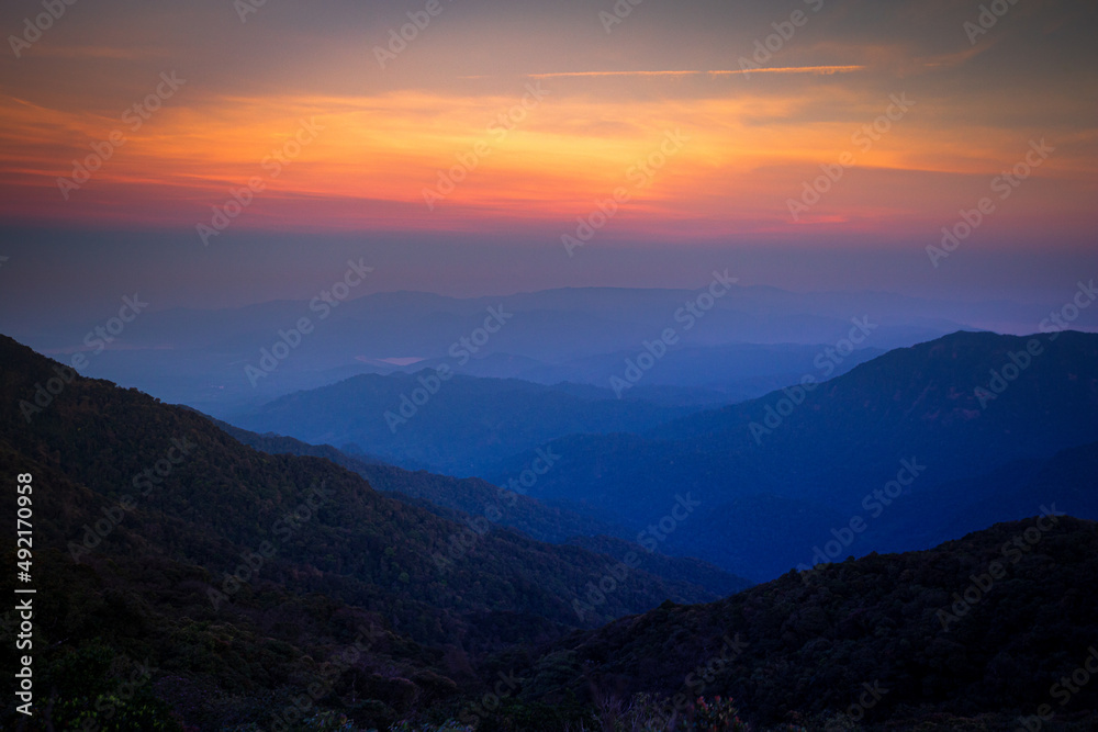 Mountains in clouds at sunrise in summer. Aerial view of mountain peak in fog. Beautiful landscape with high rocks, forest, sky. Top view from drone of mountain valley in low clouds. Foggy hills Mountains in clouds at sunrise in summer. Aerial view of mountain peak in fog. Beautiful landscape with high rocks, forest, sky. Top view from drone of mountain valley in low clouds. Foggy hills