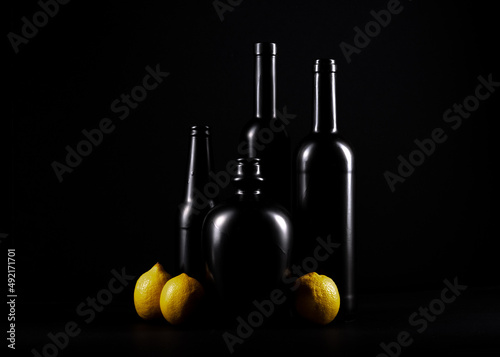 czarne butelki z żółtymi cytrynami na czarnym jednolitym tle