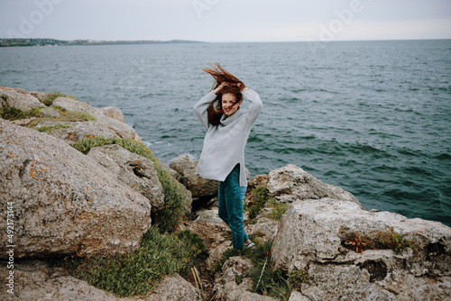 pretty woman in a gray sweater stands on a rocky shore nature unaltered © SHOTPRIME STUDIO